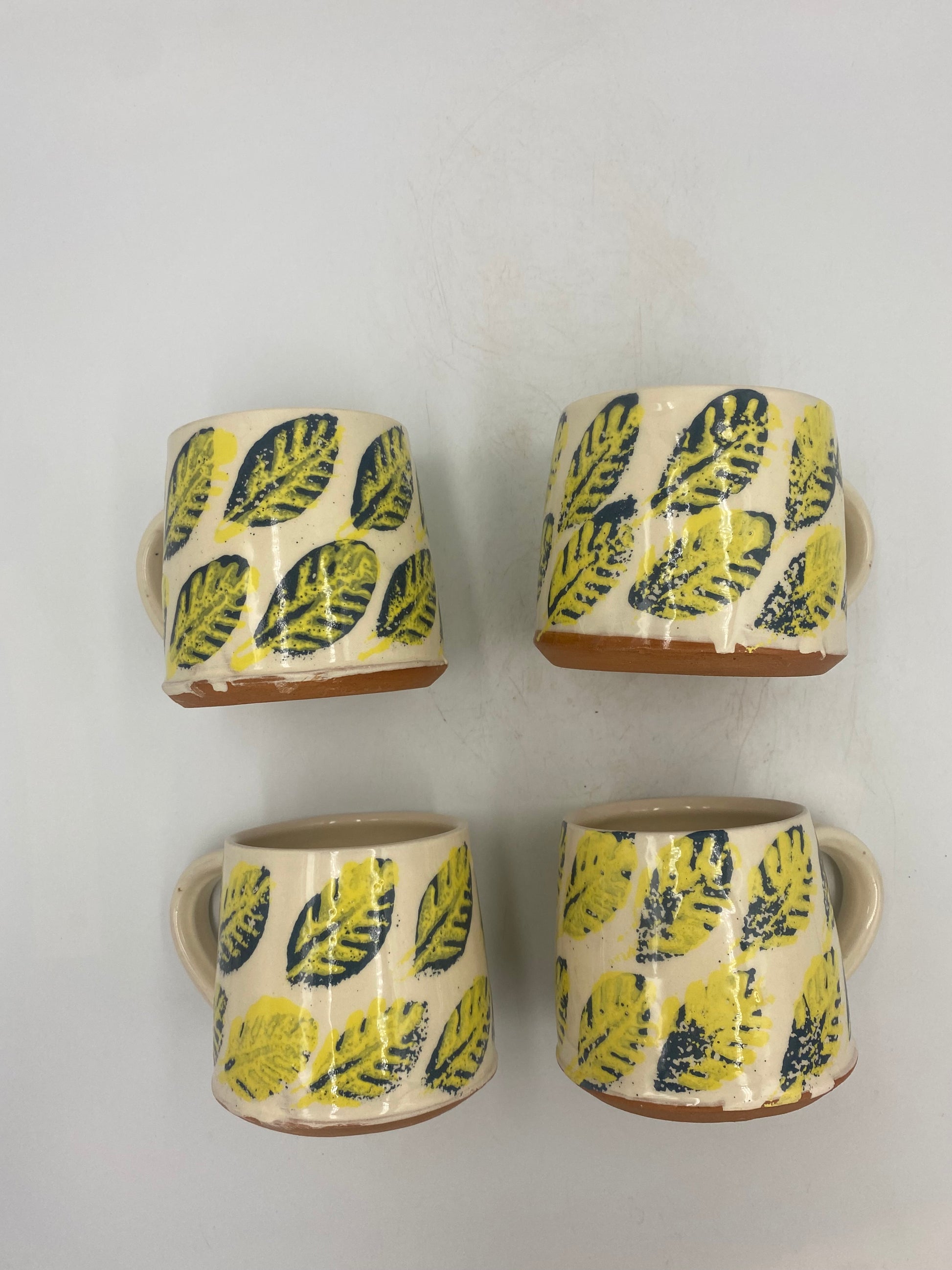 Blue and yellow leaf decoration on white background. Terracota. Hand thrown